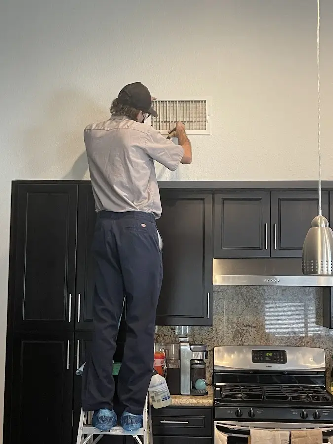 Technician inspecting an air vent during HVAC service in Hadley
